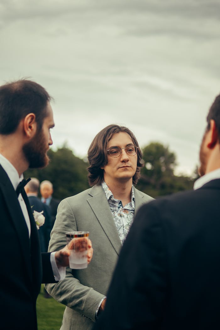 Group of men in suits conversing outdoors, showcasing style and elegance.